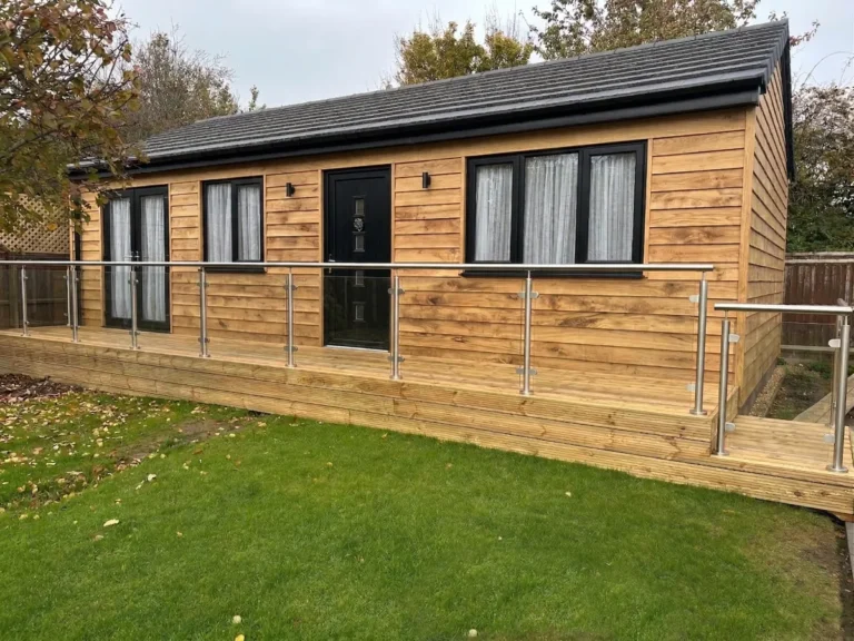 A garden view of the Beaumont annexe with green oak cladding and timber deck.
